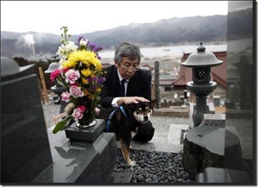 Koyu Morishita, 54, with his dog Muku, takes a moment of silence in front of his father's grave, who was killed during last year's earthquake and tsunami in Ofunato, Iwate Prefecture March 10, 2012, ahead of the one-year anniversary of the disasters. Koyu's father, Tokusaburo died at 84 years-old. REUTERS/Carlos Barria