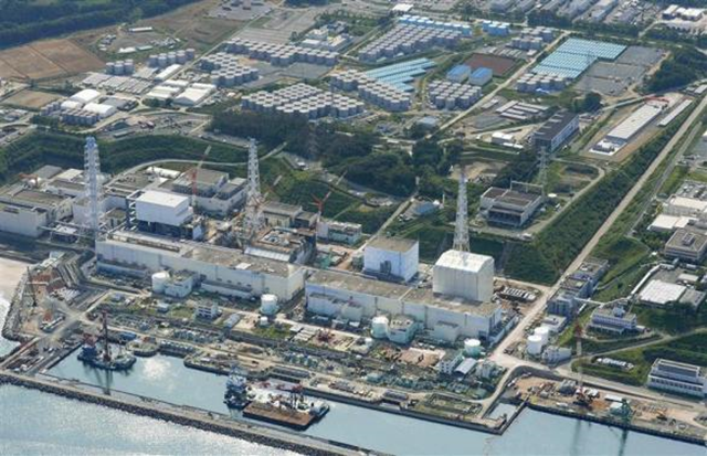 An aerial view shows the Tokyo Electric Power Co.'s (TEPCO) tsunami-crippled Fukushima Daiichi nuclear power plant and its contaminated water storage tanks (top) in Fukushima, in this photo taken by Kyodo on 31 August 2013. Storage tanks at the Fukushima nuclear plant like one that spilled almost 80,000 gallons of radioactive water in 2013 were built in part by workers illegally hired in one of the poorest corners of Japan, say labor regulators and some of those involved in the work. Photo: Reuters / Kyodo