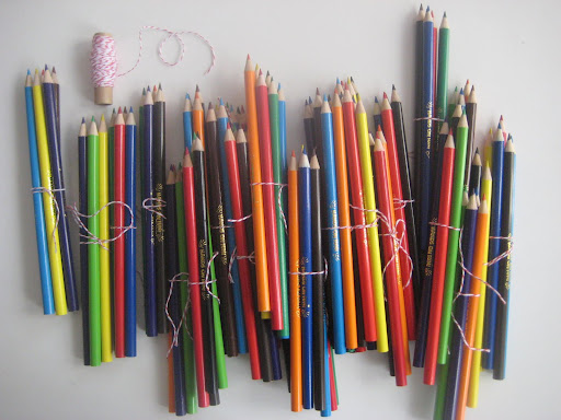 Colored pencils, bought in bulk and tied into small bundles.