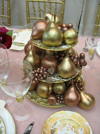 Plastic fruit that we tied into our pink and gold color palette serves as a stylish and inexpensive centerpiece. Plastic fruit that we tied into our pink and gold color palette serves as a stylish and inexpensive centerpiece.