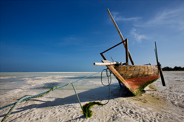 'Ephemeral Drought' by InasiaJones. Along the East Coast of Zanzibar at low tide, one can walk a long distance before touching the waves that seem kilometers away. Women of nearby villages come to collect seaweed and fishermen are returning home with their daily catch, while their boats seem out of place. Photo: InasiaJones / Trek Earth