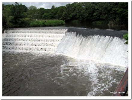 The river Irwell which is flowing quite fast over this weir.