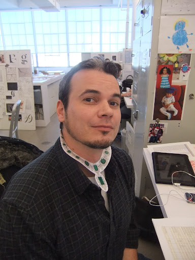 Grey Thornberry, senior design production associate, shows off his feminine side by wearing this emerald and diamond necklace.