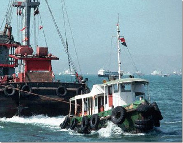 ca. 1988, Victoria, Hong Kong Island, Hong Kong, China --- Tug Pulls Barge, Hong Kong Harbor --- Image by © Carl & Ann Purcell/CORBIS
