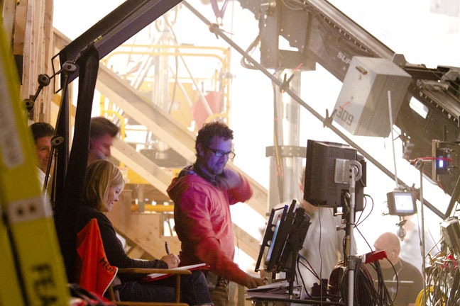 Director Tarsem Singh's face is bathed in the purple light of a playback monitor, 