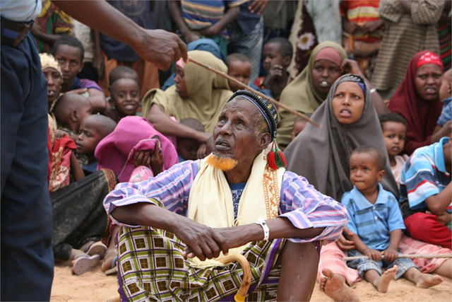 A group of newly arrived Somali refugees listens to instructions from a security officer in Dadaab, Kenya, October 2008. The conflict in Somalia has forced many people to seek refuge in northeastern Kenya. &copy; Manoocher Deghati / IRIN