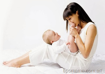 Young mother with baby boy. Sitting on white cloth and having fun. Whole bodys, side view