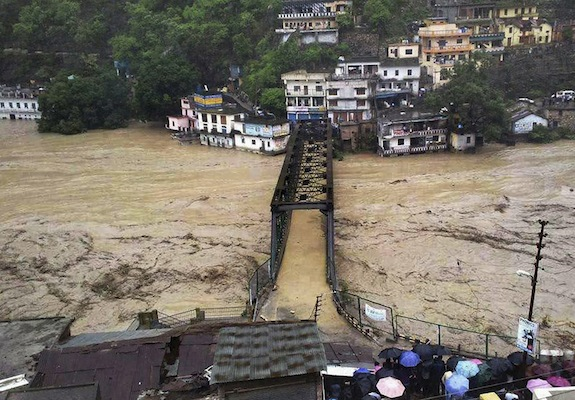 People gather to watch a bridge submerged in the flooded water of the River Ganges in Rudraprayag, in northern Indian state of Uttarakhand, India, Tuesday, 18 June 2013. Photo: AP 