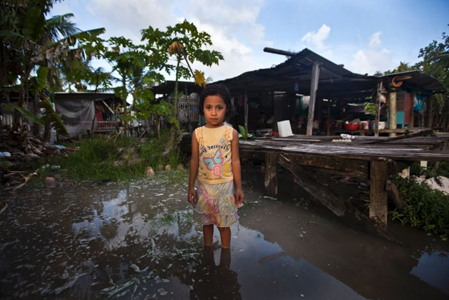 Teuga Patolo stands in king-tide waters that surround her neighbour's house, 8 December 2011. Rodney Dekker / Oxfam