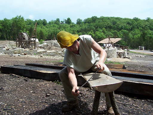 Jacon Adkins works on a bench.  He’s using a tool to shape the edges of the seat.