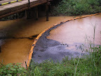 An oil spill flows down Chuuntsa Creek in Oil Block 1-AB