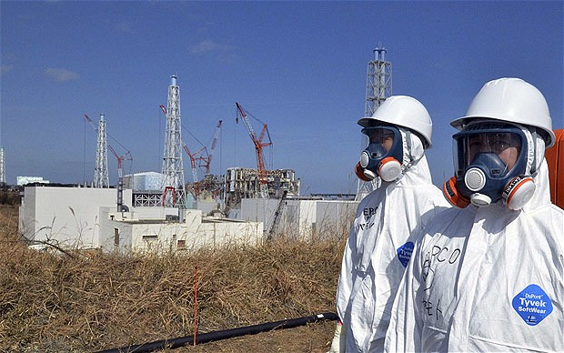 TEPCO workers stand near the crippled Fukushima Daiichi nuclear power plant reactor buildings in Fukushima, 29 February 2012.  Yoshikazu Tsuno / REUTERS via telegraph.co.uk