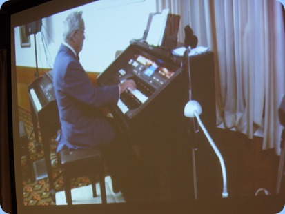 Our Special Guest Artist, Ron Clark, playing the Club's Technics GA3 organ. Ron chose themes for each of his segments which was most enjoyable. Seen here with a shot from the big screen.