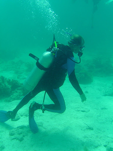 Scuba diver walking on the bottom of the sea floor, back up regulator hanging down and tank not secured.