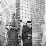 In het portiek Chrissie Nieuwpoort. Zij was die dag 100 jaar geworden. Bij haar staat haar dochter Jansie Nieuwpoort. Waarschijnlijk 1939. Zij woonden aan het oosteinde van de Bobeldijk waar eerder Freek Smit en Frouc Smit-de Haan hebben gewoond (? nummer). -Siep Kamminga-