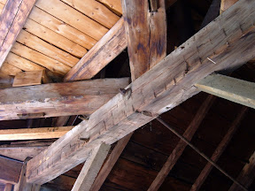 The girt with the rod attached to it has rolled on its tennons due to the weight of the sleepers that support the octagonal octagonal posts of the lantern and spire above.