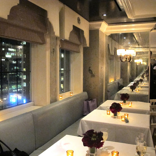 Amber candle votives and burgundy flowers multiplied in the mirrored walls.