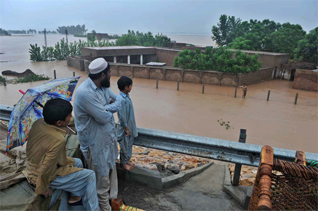 A family in Sindh province, Pakistan watches floodwaters, 12 October 2012. With nearly five million Pakistanis hit by floods that have already claimed some 400 lives, ruined tens of thousands of houses and vast swathes of crops, and left hundreds of thousands living in camps or simply under tarpaulins, the United Nations today appealed for more donations to bolster relief efforts. Abdul Majeed Goraya / IRIN