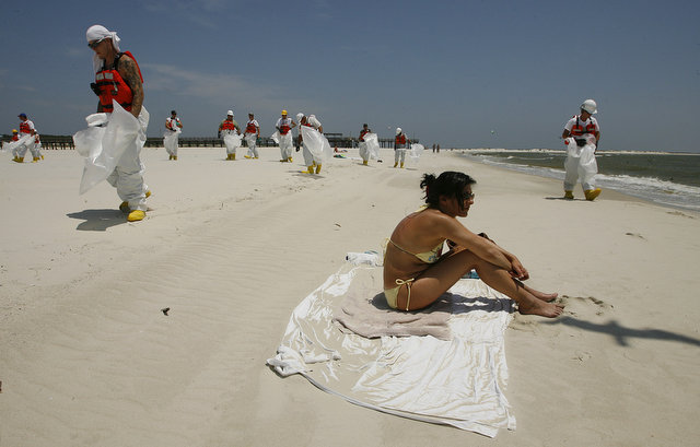 Sylvia Kellerman, on vacation from Germany, relaxes at the public beach as workers in protective suits look for tar balls Wednesday, May 12, 2010, in Dauphin Island, Alabama. Mike Kittrell / Press-Register