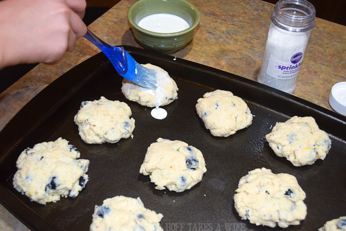 how to brush cream on scones. A melt in your mouth recipe for blueberry scones. Inspired by Starbucks in house version, this blueberry scone with hints of lemon and a crunchy sugary top will delight everyone. Serve during High Tea, or just as a mid afternoon snack. Perfect along side tea or coffee, or as a stand alone blueberry dessert. You won't believe how easy these are to make! Never made scones before? Never fear, this includes a step by step tutorial on how to make scones. #HighTea #blueberries #Starbucks #scones #dessert How to brush cream on scones