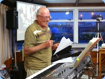 Laurie Conder enjoying the moment as he sets-up his Roland G-70 keyboard. Laurie threw darts at the audience with a list of songs on them. The recipients in the audience got to choose the next song! Photo courtesy of Dennis Lyons.