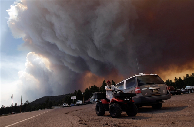 Robert Joseph rides his ATV as smoke plumes from the Wallow fire fill the sky in Luna, N.M., Monday, June 6, 2011. Firefighters worked furiously Monday to save a line of mountain communities in eastern Arizona from a gigantic blaze that has forced thousands of people from their homes and cast a smoky haze over states as far away as Iowa. Jae C. Hong / AP