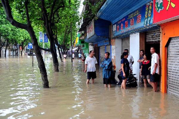 People stand outside a waterlogged store in Fangchenggang City, south China's Guangxi Zhuang Autonomous Region, 18 August 2012. Typhoon Kai-Tak has affected about 1.26 million people and 134,470 hectares of farmlands in Guangxi till 4:30 p.m. Saturday. Local flood control authority initiated a Level IV emergency response to cope with the possible flooding. Xinhua / Huang Xiaobang
