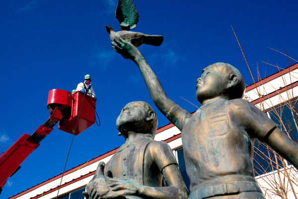 A radiation decontamination worker is lifted onto the roof of a school gym in Iitate, Japan. Ko Sasaki for The New York Times