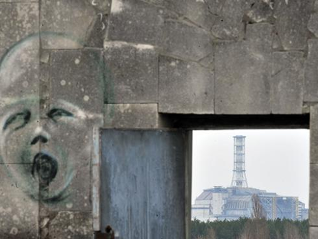 A graffiti is pictured on a wall in the ghost city of Pripyat near the fourth nuclear reactor (background) at the former Chernobyl Nuclear power plant. Tours to the site have been suspended. SERGEI SUPINSKY / AFP / Getty Images