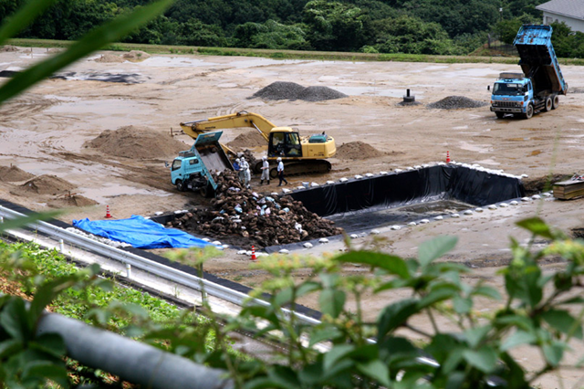 Dump trucks unload bags containing radioactive dirt at a temporary disposal site in Fukushima Prefecture on 28 July 2011. Satoru Murata / Asahi Shimbun