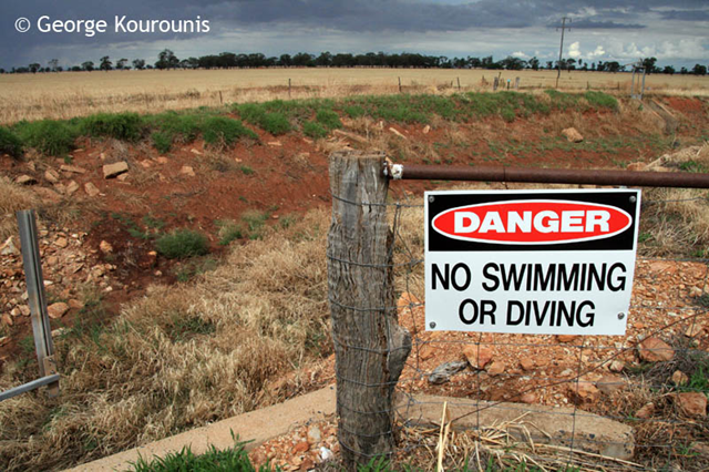 A sign reads 'Danger - No Swimming or Diving' above an empty irrigation canal in Australia,  December 2007. George Kourounis / www.stormchaser.ca