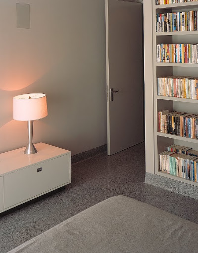 A cast-aluminum base lamp sits atop a low cabinet in the guest bedroom; in a nearby bookcase, Alexis stores her well-read collection of paperbacks.