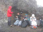 Lunch in the shelter of a rock to protect us from the blowing rain. Steven, Simina, Matt, Maggie.