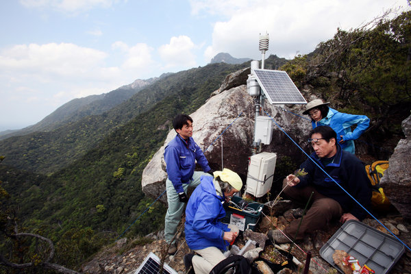 Osamu Nagafuchi, second right, an environmental engineer, checks a monitoring station around Yakushima to measure levels in the air of ozone and sulfur emissions, which are typically the byproducts of burned coal or automobile exhaust. Mr. Nagafuchi believes air pollution from China is killing endangered trees in Japan. Photo: Kosuke Okahara / The New York Times