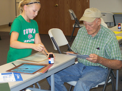 Highlanders 4-H member Kiley Wood, daughter of Brian and Angie Wood, worked with her grandpa Dean Schoon to create several pieces of art at the 4-H Photo Mounting Day.  Photo courtesy:  Washington County Extension.