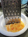 Grating cheddar cheese.