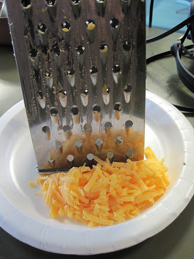 Grating cheddar cheese.