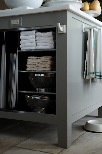 A kitchen island can make the perfect storage area. Here, baking sheets are sorted vertically, mixing bowls sit on shelves and towels can be both folded on shelves or hung from a hook. A kitchen island can make the perfect storage area. Here, baking sheets are sorted vertically, mixing bowls sit on shelves and towels can be both folded on shelves or hung from a hook.