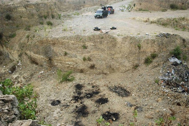 The site of a mass grave with some charred spots (rear) is seen in the suburb of Juarez, neighbouring Monterrey, July 22, 2010. Forensic investigators and the military found the remains of at least fifty people so far, suspected to be victims of drug crimes, in one of two mass graves discovered on Thursday in this municipality, according to local media. Picture taken July 22, 2010. Reuters