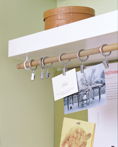 Here, cup hooks and a drapery rod function as a place to display photos and business cards.