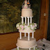 Nº170: Terminación en fondant blanco y marfil, lazos, rosas de pasta de goma, perlas comestibles. Montaje tradicional sobre pilares.