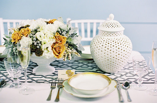 Blanc de Chine vases along with gorgeous gold-trimmed fine china, silver utensils, and a chain-link table runner helped create a beautiful tablescape.