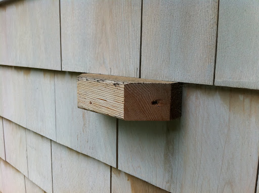 I made blocks out of cedar and attached them to the house. The trellis is mounted on the blocks to ensure that there is some space between the trellis and exterior of the house.
