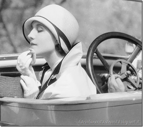 Actress Norma Shearer powdering her chin while sitting in the passenger seat of a car, 1929