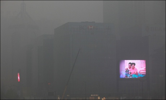 A big screen flashes commercials on the exterior of an office building in Xi'an in north-west China as the air quality index reaches 282 due to pollution. Photo Mayi Wong / EPA