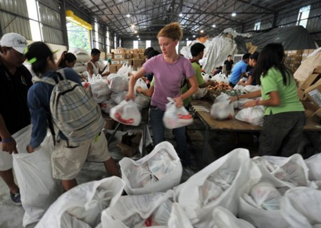 Volunteers are seen packing assorted relief food at the social welfare operation center in Manila, on 14 August 2012, for distribution to thousands of flood-affected residents throughout the capital amidst the threat of a new storm. AFP