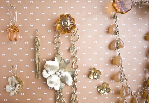 To make the jewelry display case, Anthropologie drawer pulls were screwed into the bottom of an old dresser drawer lined with pretty paper. It can also be used to hold hanging elements, like tag escort cards, at your wedding.