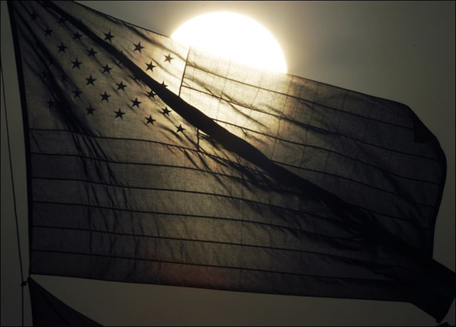 The sun sets behind an American flag on Thursday, 21 July 2011 in Lawrence, Kansas. ASSOCIATED PRESS