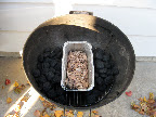 We use a Weber charcoal grill. An aluminum pan is set in middle of the bottom grill rack and filled with wood chips and water. Charcoal is then mounded on both sides of the pan. We use a Weber charcoal grill. An aluminum pan is set in middle of the bottom grill rack and filled with wood chips and water. Charcoal is then mounded on both sides of the pan.