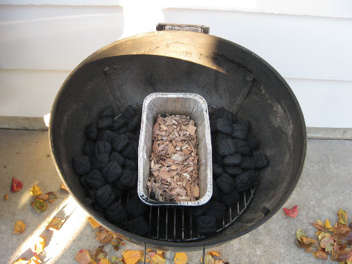 We use a Weber charcoal grill. An aluminum pan is set in middle of the bottom grill rack and filled with wood chips and water. Charcoal is then mounded on both sides of the pan. We use a Weber charcoal grill. An aluminum pan is set in middle of the bottom grill rack and filled with wood chips and water. Charcoal is then mounded on both sides of the pan.